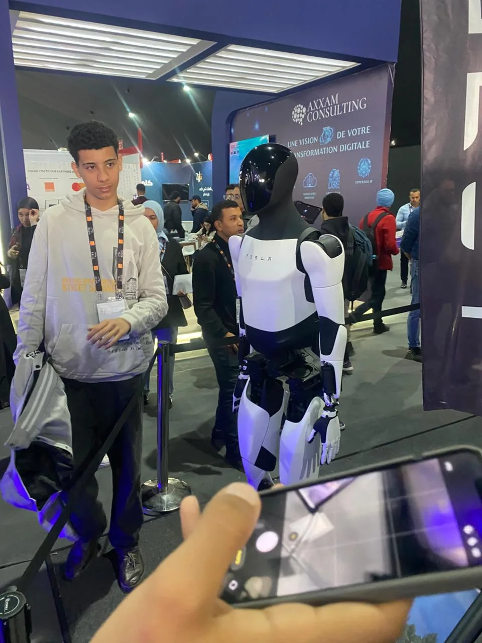 Visitor taking photos with Tesla Optimus robot at GITEX Africa